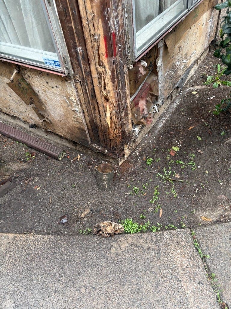 Badly damaged corner post at the base of an exterior wall